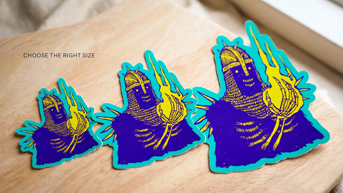 The same die-cut sticker design shown in small, medium, and large sizes on a wood table.